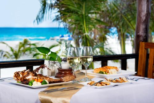 a table with two plates of food and glasses of wine at Flamingo Cancun All Inclusive in Cancún
