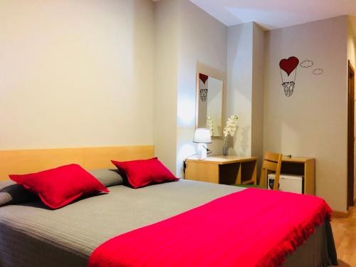 a bedroom with a large bed with red pillows at Hotel Viñas 17 in Teruel