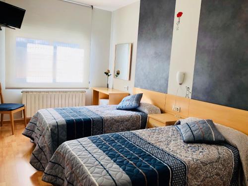 Una habitación de hotel con dos camas y un televisor. en Hotel Viñas 17, en Teruel