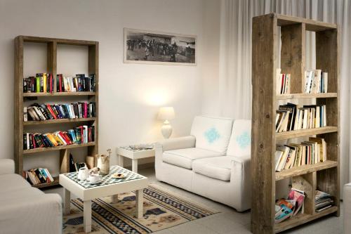 a living room with a couch and a chair and bookcases at Gabbiano Azzurro Hotel & Suites in Golfo Aranci