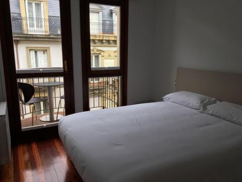 サン・セバスティアンにあるSan Marcial by Basquelidaysのベッドルーム1室(ベッド1台、大きな窓2つ付)