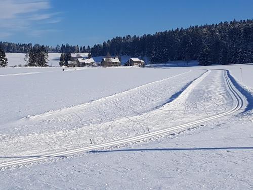 a snow covered field with tracks in the snow at La Clé des Champs in Les Fourgs