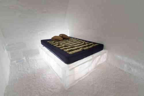 a bed in a white room with two shoes on it at Hotel de Glace in Saint-Gabriel-De-Valcartier