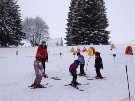 a group of children on skis in the snow at La Clé des Champs in Les Fourgs