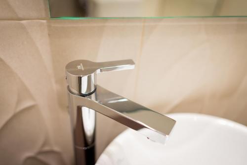a bathroom with a toilet with a chrome faucet at Cuatro Caminos Rooms in Torrelavega