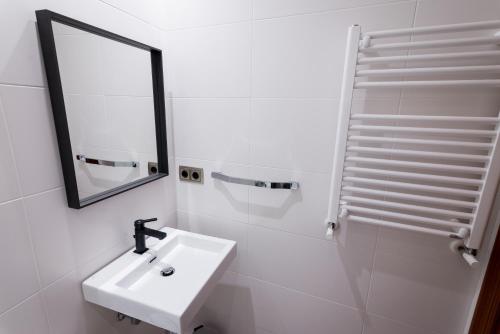 a white bathroom with a sink and a mirror at Cuatro Caminos Rooms in Torrelavega
