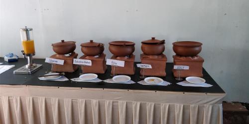 une table avec des casseroles en argile et des assiettes sur une table dans l'établissement Exotica Beach Retreats Diveagar, à Diveagar