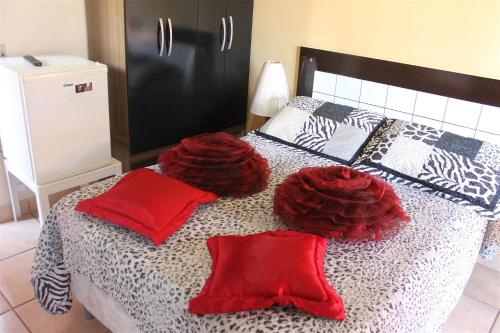 a bedroom with a bed with red pillows on it at Pousada da Lenna in Rio das Ostras