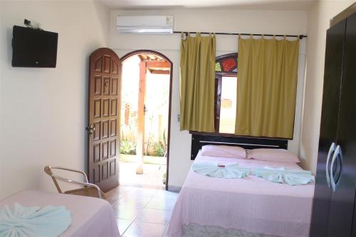 a bedroom with a bed and an open door at Pousada da Lenna in Rio das Ostras