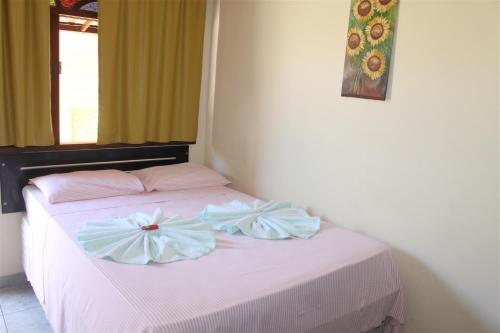 a bedroom with a pink bed with bows on it at Pousada da Lenna in Rio das Ostras