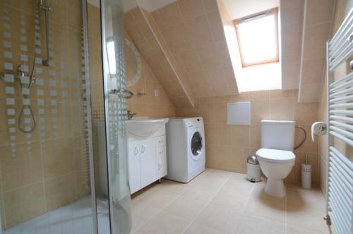 a bathroom with a toilet sink and a washing machine at Station House Loft Apartment in Obrataň