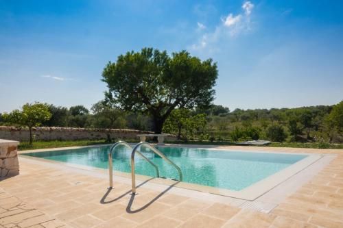 uma piscina com um corrimão de metal ao lado de uma árvore em Trullo la Quiete em Alberobello