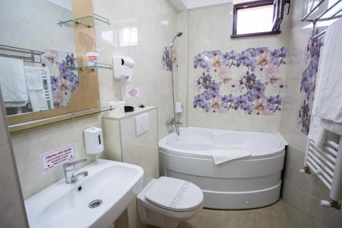 a bathroom with a white toilet and a sink at Hotel-Restaurant Ayan Piatra Neamt in Piatra Neamţ