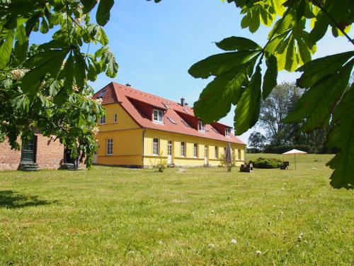 uma casa amarela com um telhado vermelho num campo em Ferienhaus Gut Rattelvitz Insel Rügen em Gingst