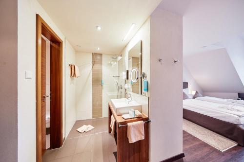 a bathroom with a sink and a bed and a mirror at Die Reichsstadt - Hotel Spa und Restaurant in Gengenbach