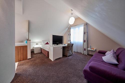a living room with a purple couch and a tv at Die Reichsstadt - Hotel Spa und Restaurant in Gengenbach