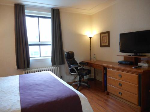 a bedroom with a bed, desk and television at Hotel St-Denis in Montreal