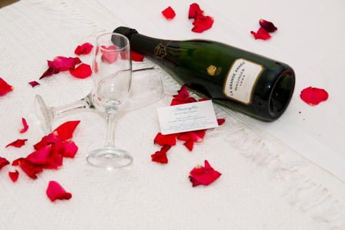 a bottle of wine and two glasses with red flowers at Amaryllis in Plataniás