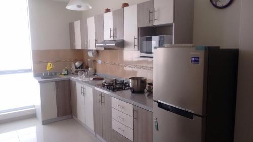 a kitchen with white cabinets and a refrigerator at Departamentos Playa San Bartolo in San Bartolo