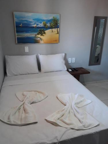 a bed with white sheets and towels on it at Suítes Canaã in Canoa Quebrada
