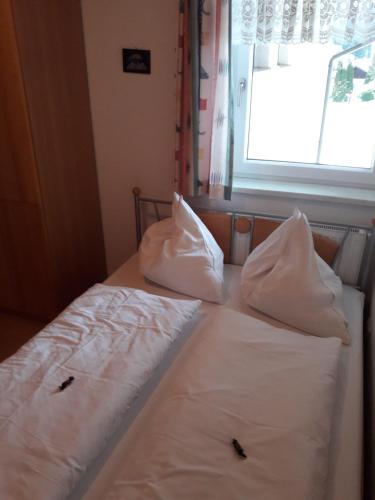 a bed with white sheets and pillows with a window at Ferienwohnung Kupfer in Göstling an der Ybbs