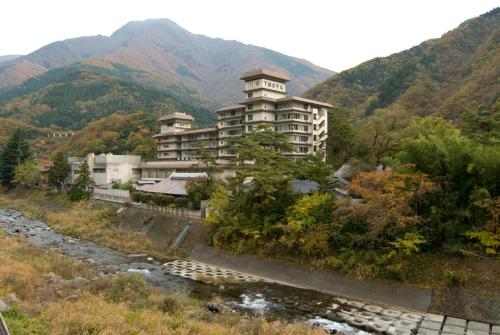 a building next to a river with mountains in the background at Shimobe Hotel in Minobu
