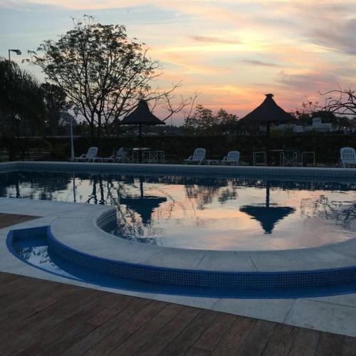a swimming pool with chairs and a sunset in the background at IRUPÉ APART HOTEL in Federación