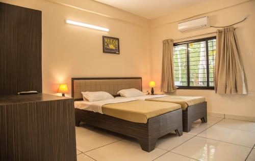 a bedroom with two beds and a window at Hotel Arambol Arbour in Arambol