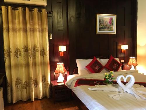 a bedroom with a bed with two swans on it at Villa Phathana Royal View Hotel in Luang Prabang