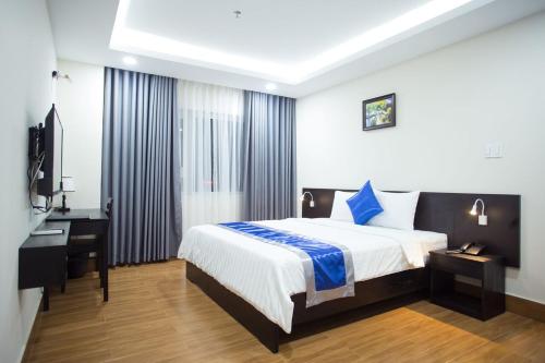 Dormitorio con cama, escritorio y TV en SoLex Hotel en Ho Chi Minh