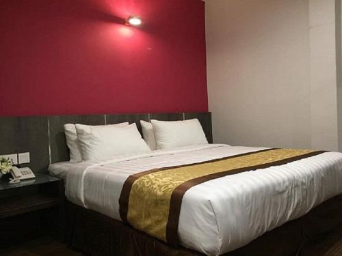 a bedroom with a large bed with a red wall at Meriton Inn in Kuantan
