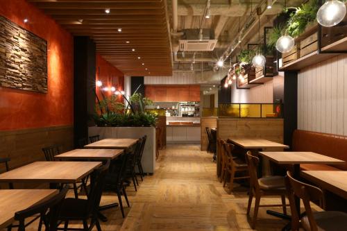 um restaurante com mesas e cadeiras de madeira e uma cozinha em Hotel Wing International Select Nagoya Sakae em Nagoya