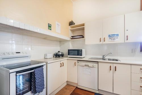 a white kitchen with white cabinets and appliances at Halswell Lodge in Wellington