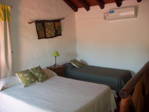 a bedroom with two beds and a lamp and a window at Casitas Volver a Nacer in Carpintería