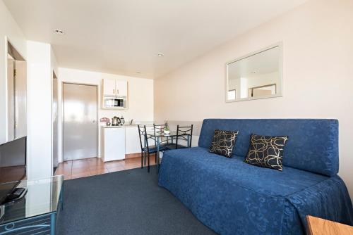 a living room with a blue couch and a kitchen at Halswell Lodge in Wellington