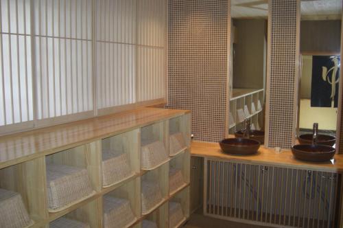 a room with wooden shelves with bowls on them at Ryokan Kousen Kazeya Group in Nara