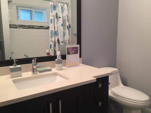 y baño con lavabo, aseo y espejo. en Vancouver Austin Guesthouse en Coquitlam