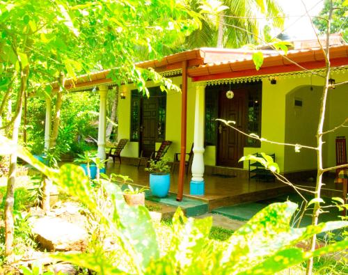 a small yellow house with a wooden porch at Senura Home Stay in Sigiriya