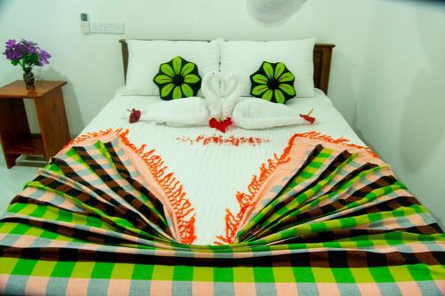 a bed with a blanket and pillows on it at Senura Home Stay in Sigiriya