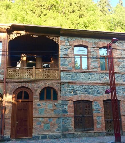 Casa de piedra con puerta de madera y balcón en Inka home en Borjomi