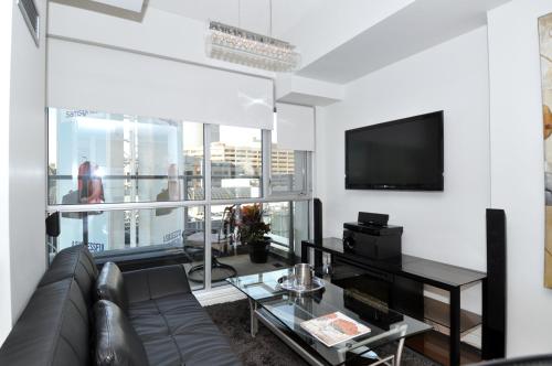 a living room with a couch and a flat screen tv at Yonge Suites Apart Hotel in Toronto