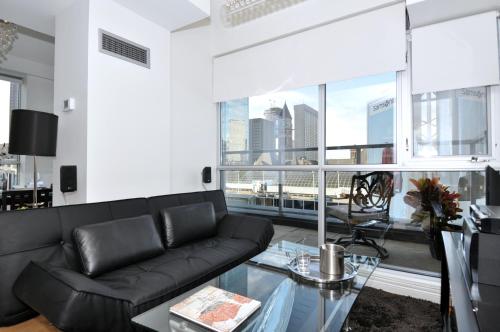 a living room with a black couch and a glass table at Yonge Suites Apart Hotel in Toronto