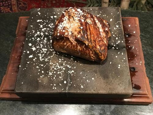 a piece of cake sitting on top of a wooden cutting board at Le Charaban in Aosta