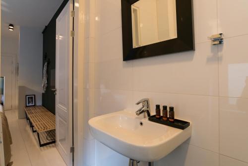 ein weißes Bad mit einem Waschbecken und einer Dusche in der Unterkunft Canal Suite City Centre in Amsterdam