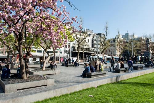 people sitting on benches in a park with trees at Canal Suite City Centre in Amsterdam