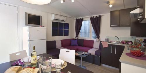 a small kitchen and a living room with a purple couch at Camping villaggio L'Ultima spiaggia in Bari Sardo