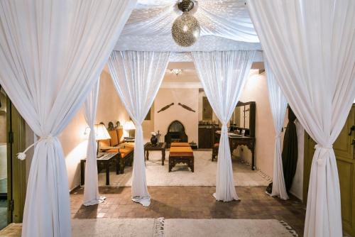 Almaha Marrakech Restaurant & SPA في مراكش: غرفة مع ستائر بيضاء وغرفة معيشة