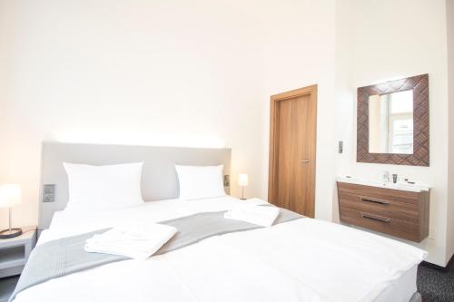 a white bedroom with a large bed and a sink at Narodni Stay in Prague