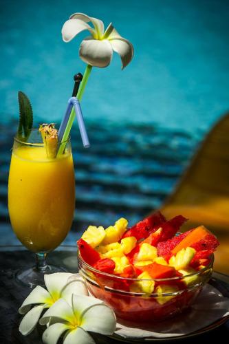 uma tigela de frutas, uma bebida e uma flor em Papa Jolly Eco Resort-Near Morjim Beach em Morjim