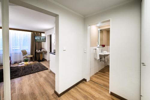 a hallway with white walls and a bathroom with a sink at Apartments Butterfly Zermatt in Zermatt